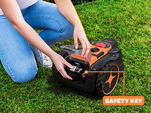 Person inserting safety key into a lawn mower on grass.