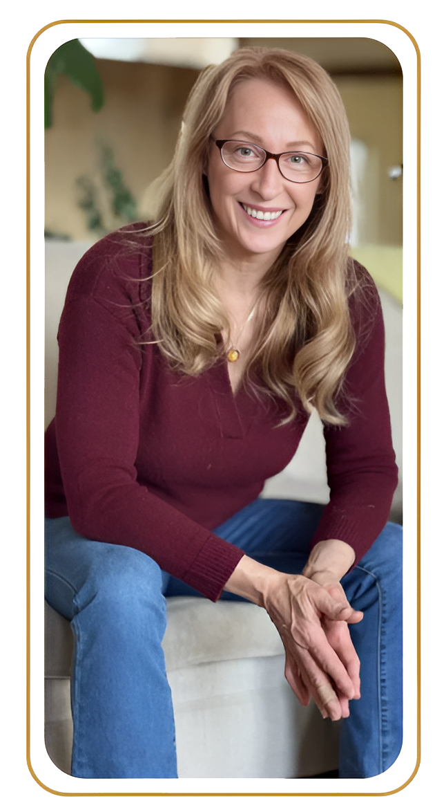 Smiling person sitting on a couch, wearing a maroon sweater and blue jeans.