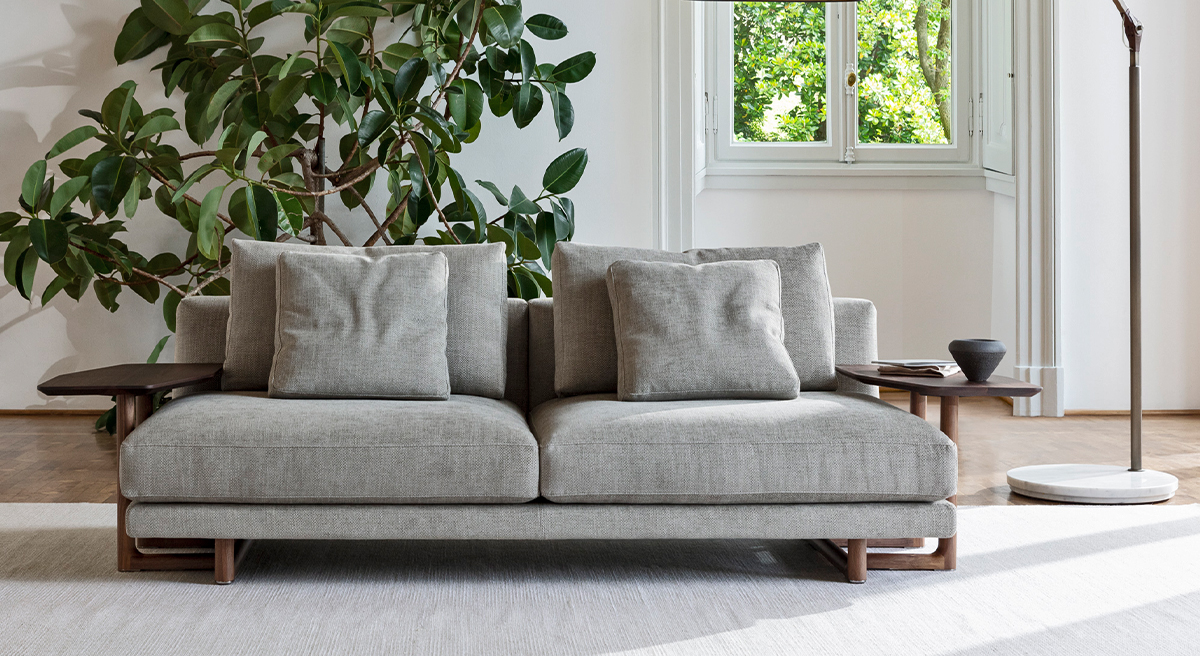 Modern Porada sofa with cushions, plant, and floor lamp in a bright room.
