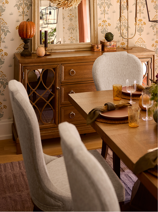 Warm dining room vignette with seasonal decor, wood furnishings, and upholstered seating.