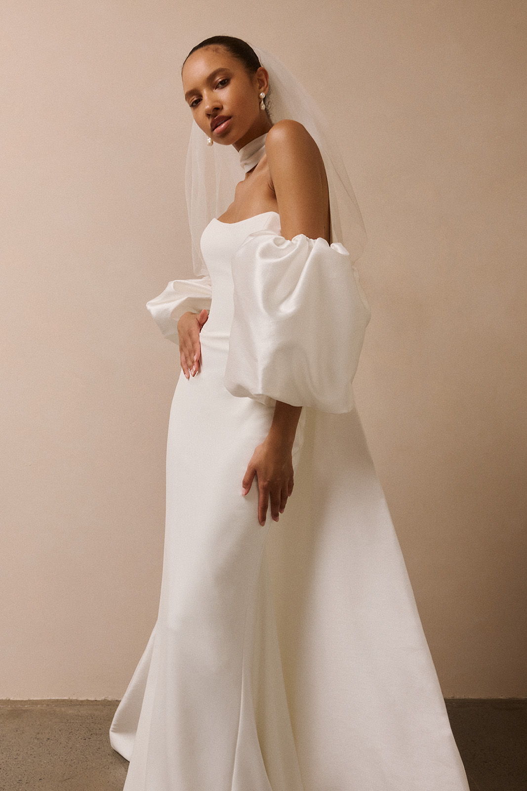 Bride in elegant white wedding dress with puffed sleeves and veil.