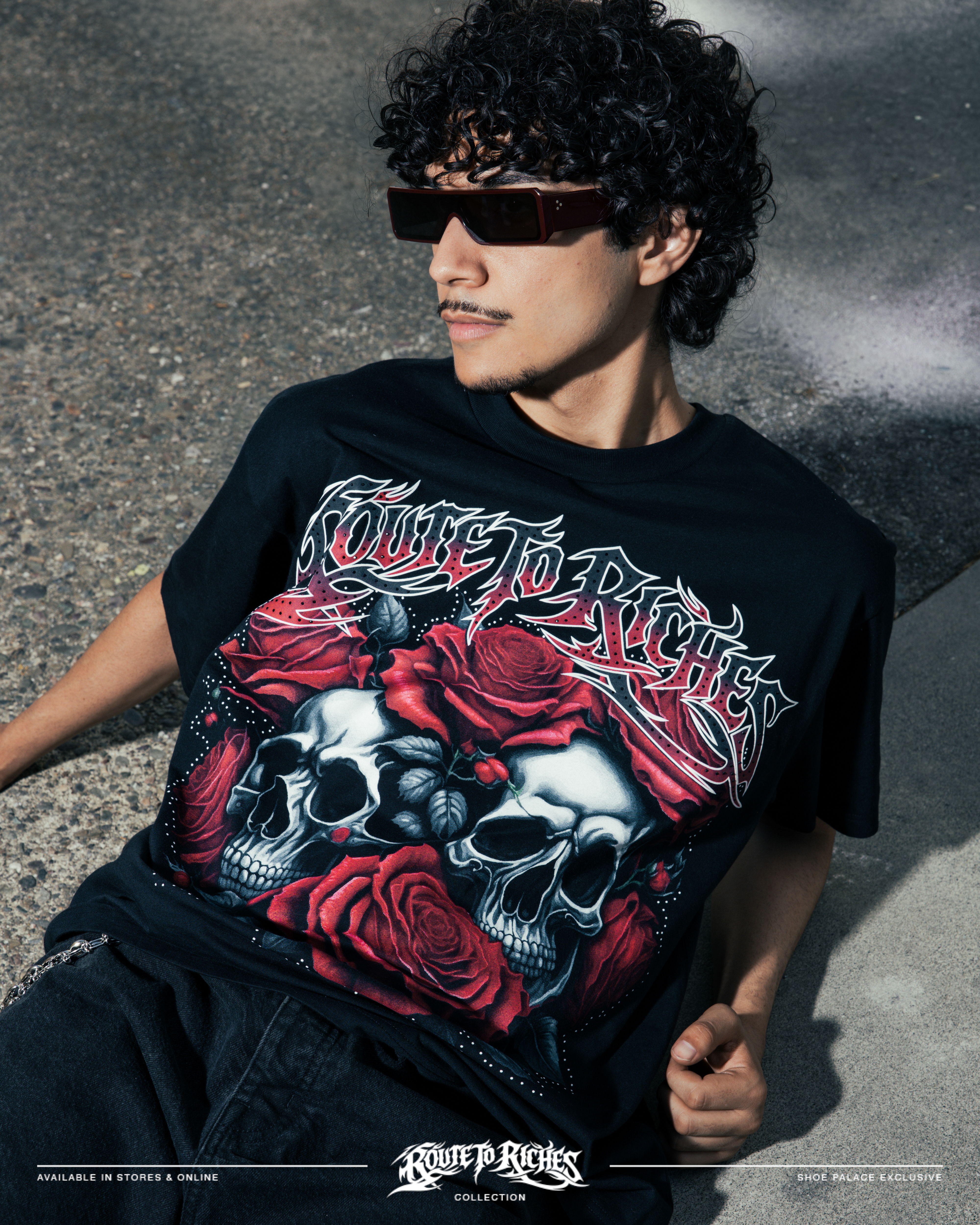 Person wearing a graphic t-shirt with skulls and roses, posing outdoors.