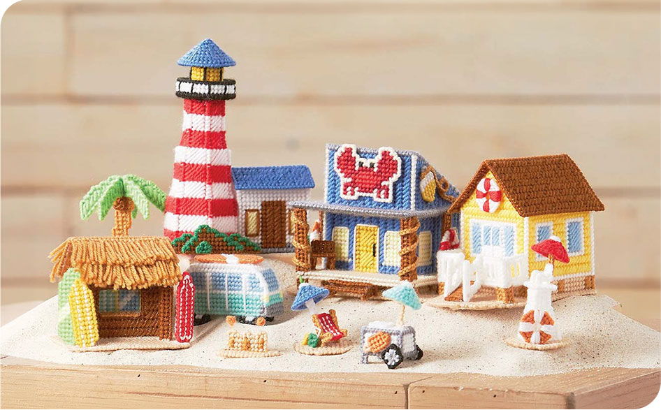 Colorful miniature beach scene with a lighthouse, houses, and palm trees.