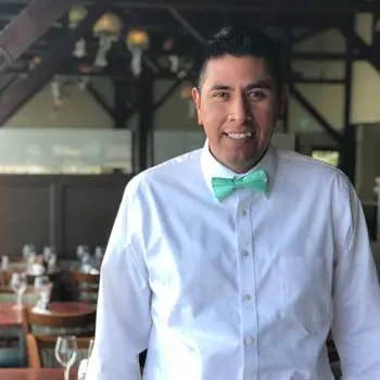 A waiter wearing a seafoam bow tie.