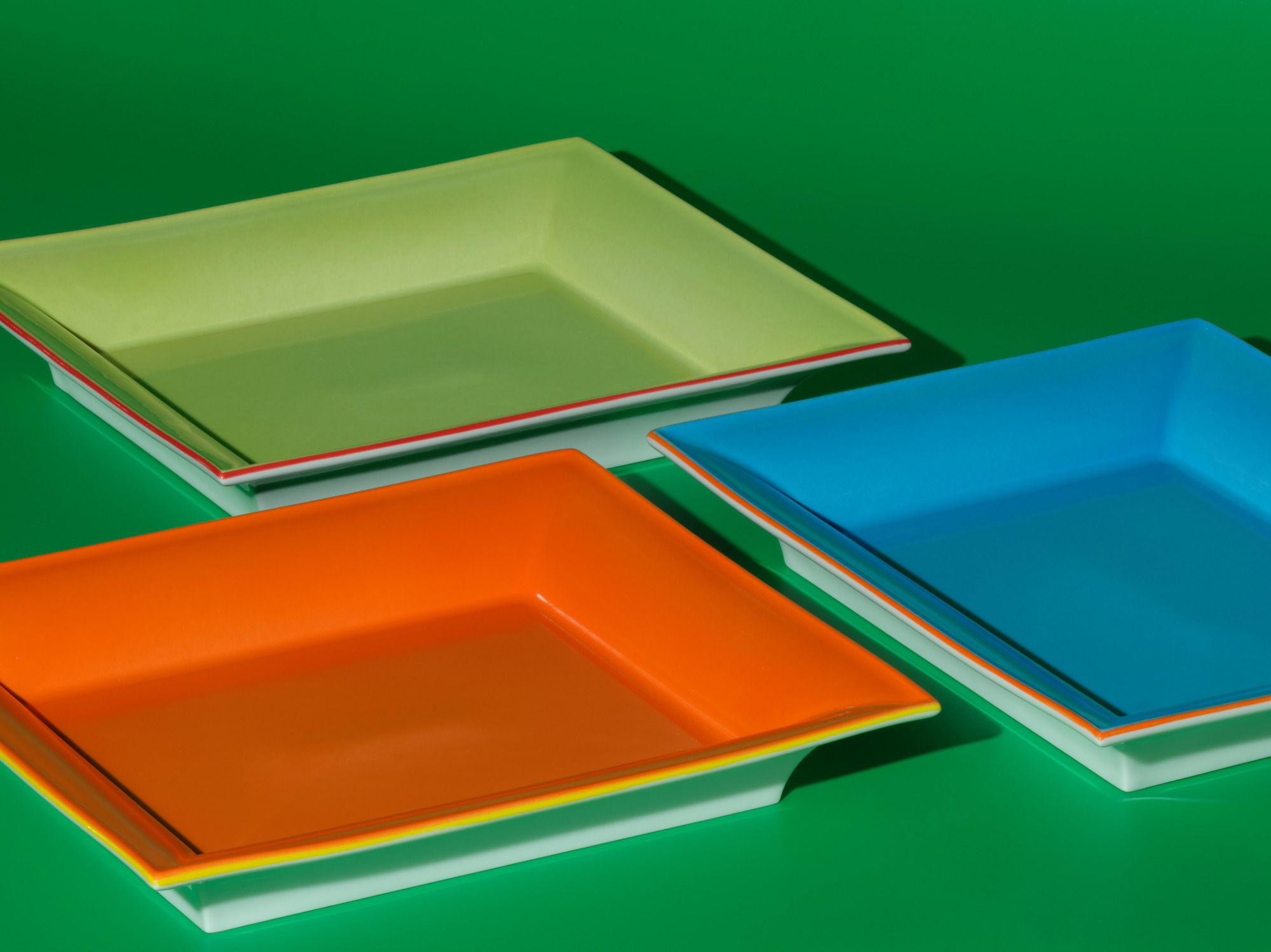 Three colorful, square plates on a green background.