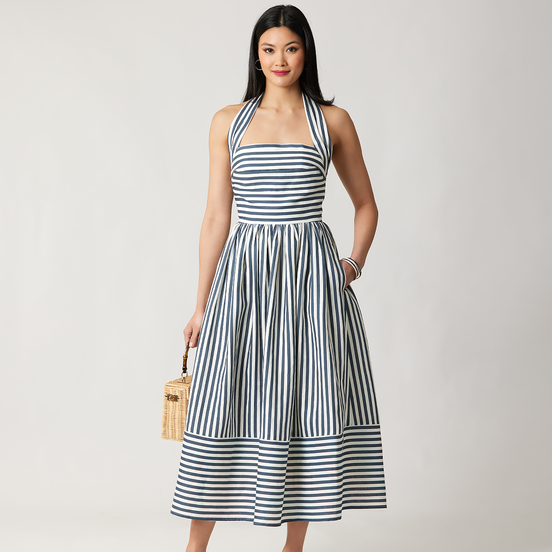 A woman in a striped dress holding a small bag.