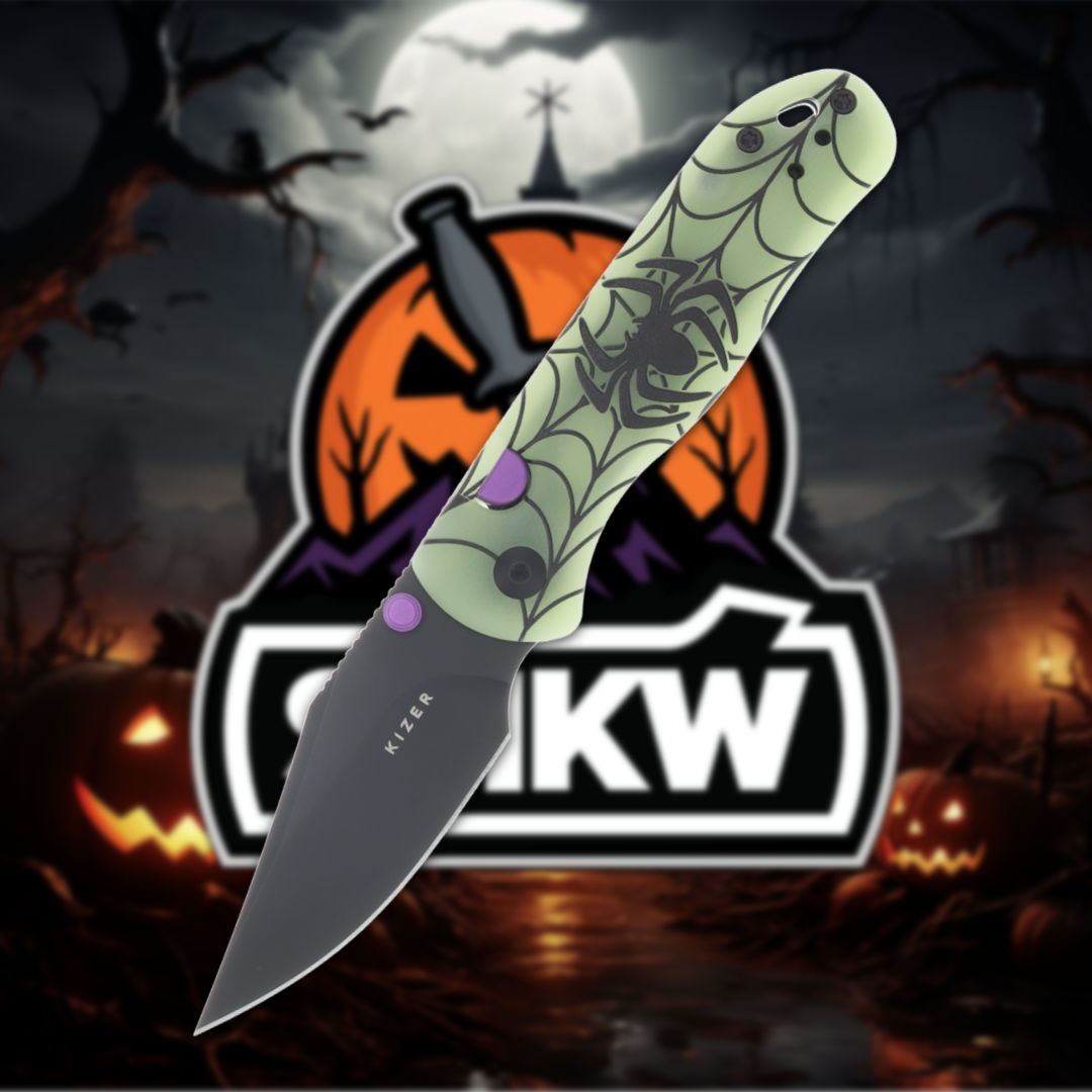 A knife with a green spider-themed handle against a Halloween backdrop.