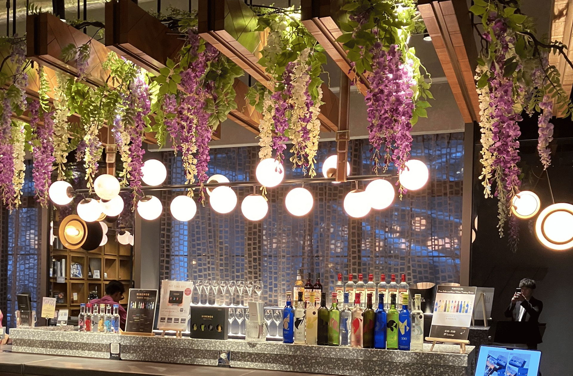 A stylish bar with hanging lights and floral decorations.