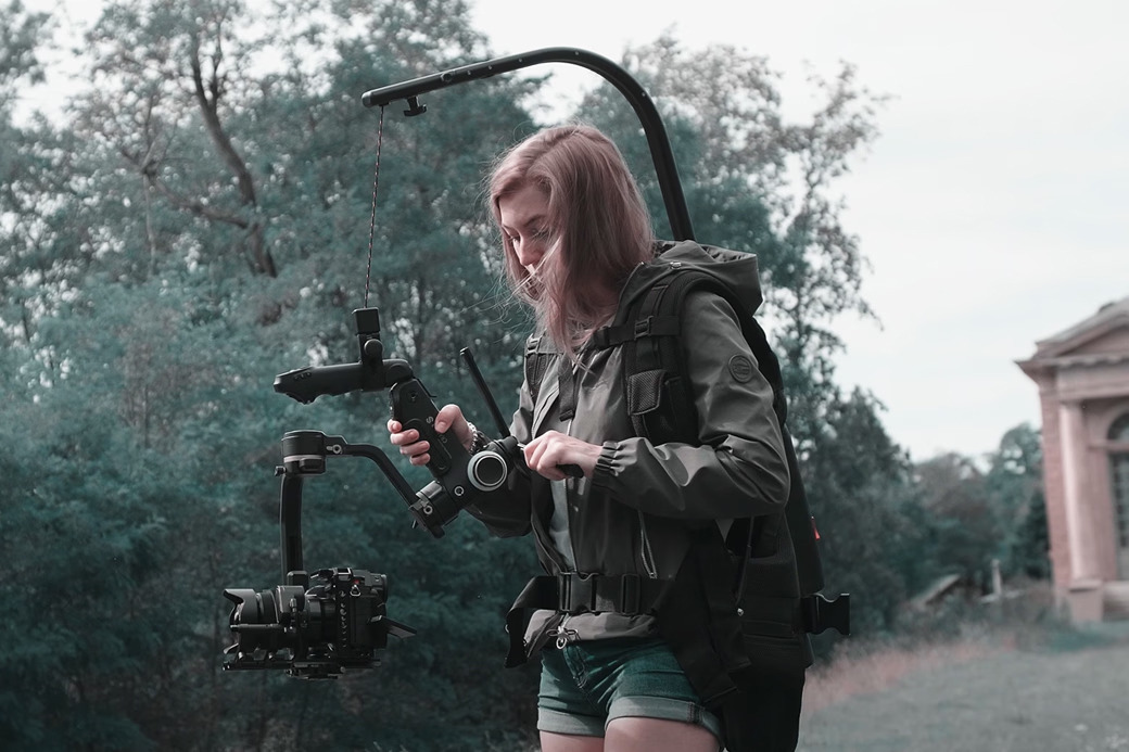 Person operating a camera stabilizer in an outdoor setting.