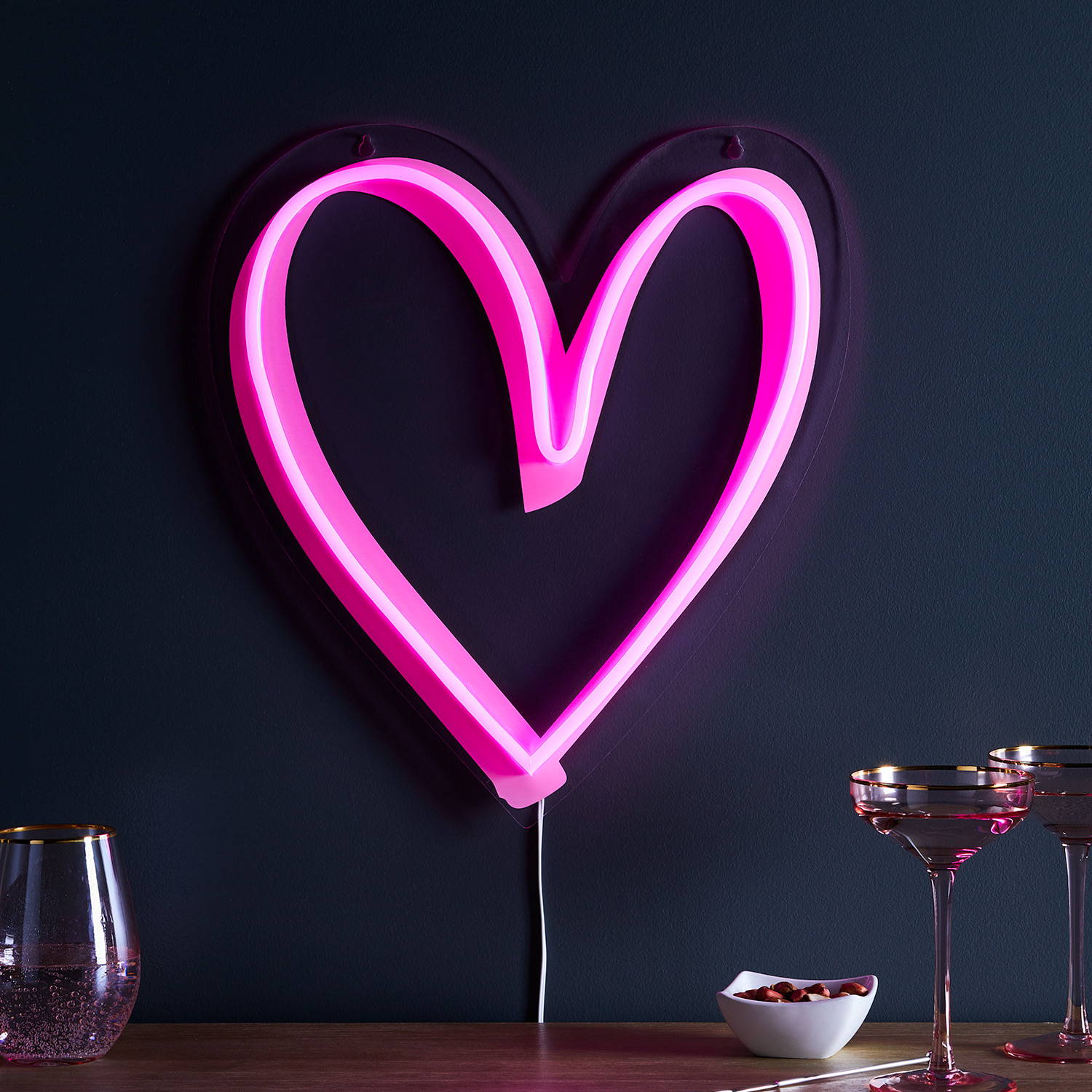 Pink neon heart light illuminated on dark wall