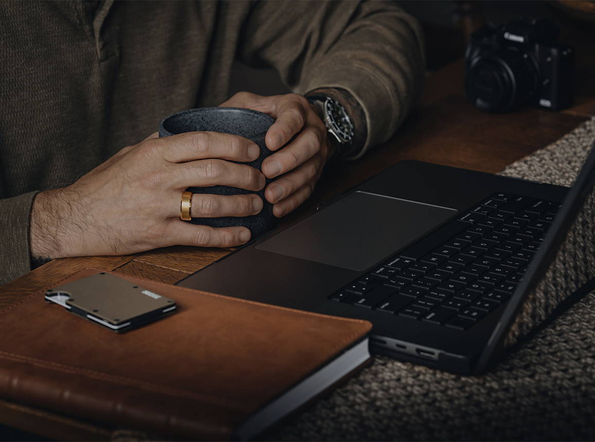 мъж пред компютър с пръстен от 24-каратово злато Ridge 8MM Beveled Ring, който носи на пръста си