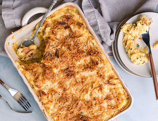Baked potato casserole with a crispy cheese topping, served with a side plate.