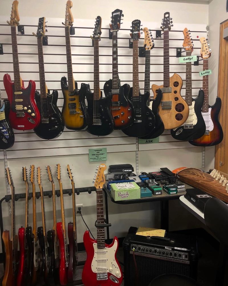 Guitars displayed on a wall and a table with an amplifier.