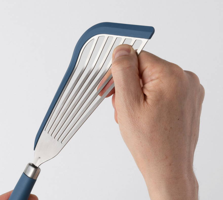 Close view of hand pinching the slotted metal surface of a Blue Misen Silicone Fish Spatula’s head.