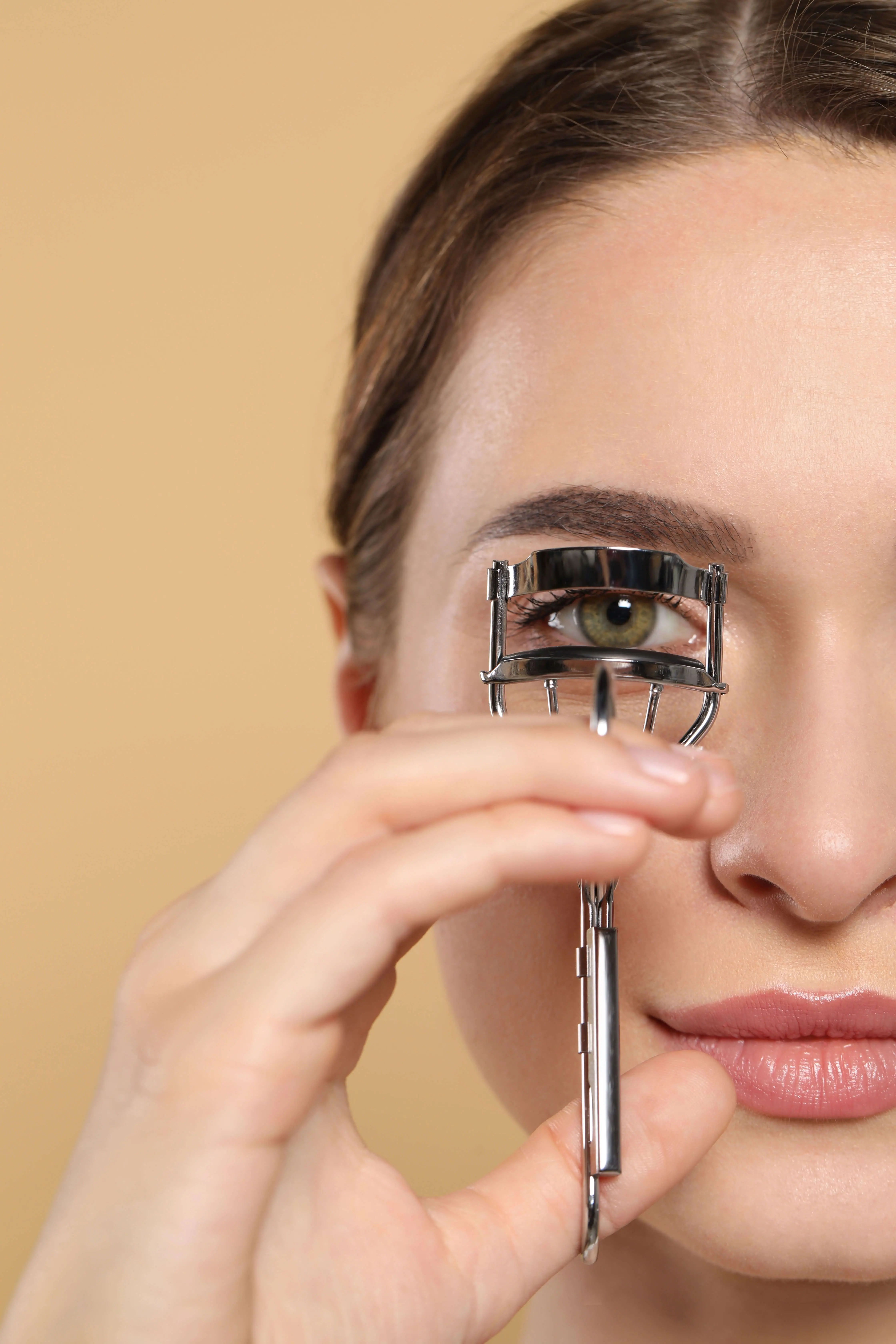 Person using an eyelash curler on their eyelashes.