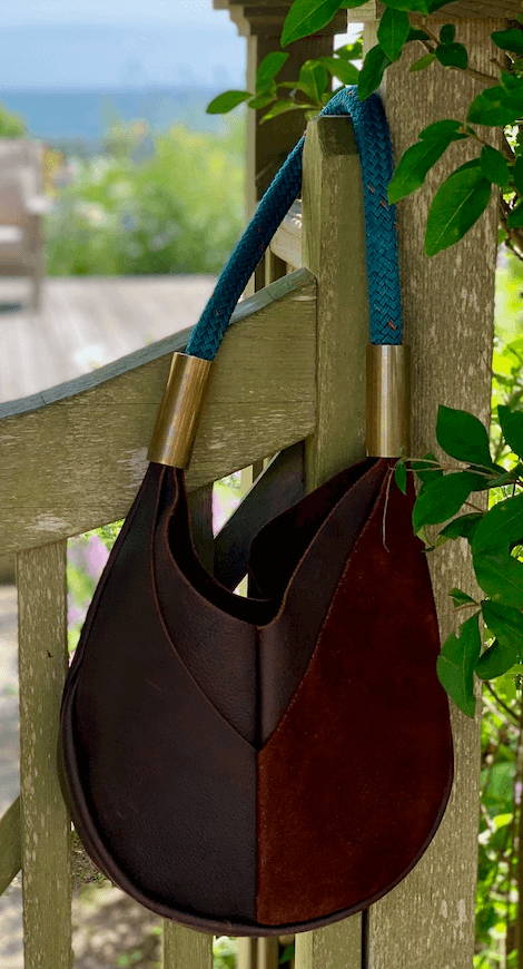leather bag with teal strap hooked on fence