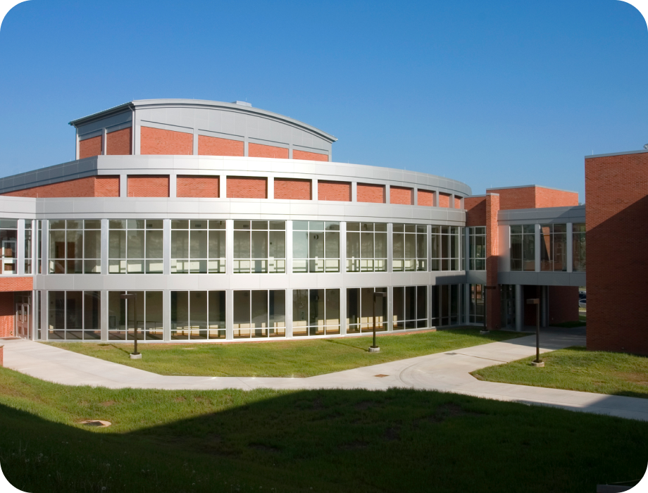 Modern building with large windows and a grassy area in front.