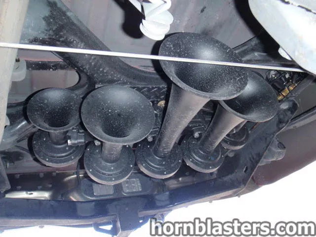 Low-angle underside view four black Nathan Airchime train horn trumpets mounted on bracket road dust chassis Dennis's 2000 Toyota Tundra K5 install gallery photo 2