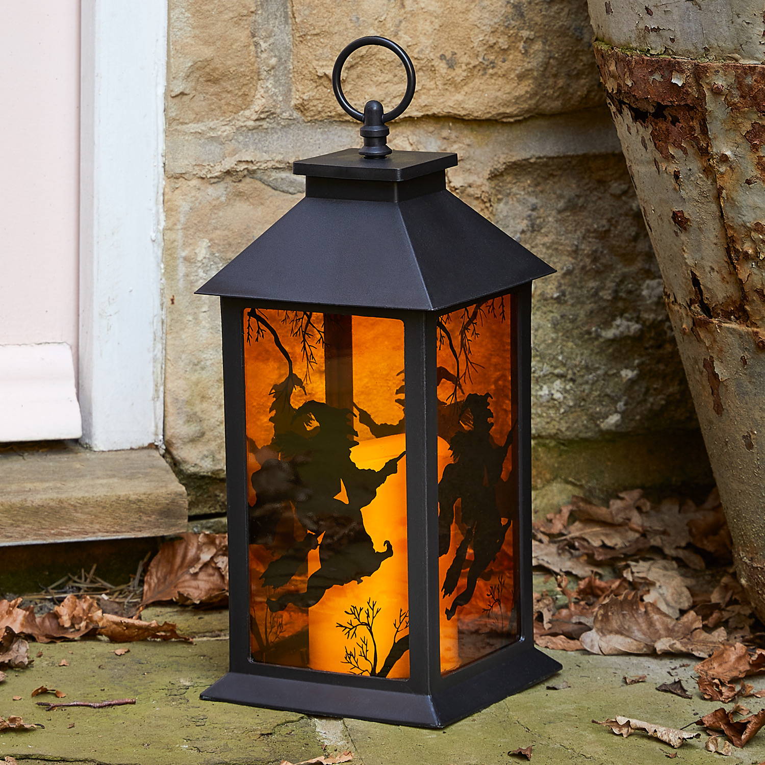 Outdoor halloween lantern with tinted orange glass sides and a witch design