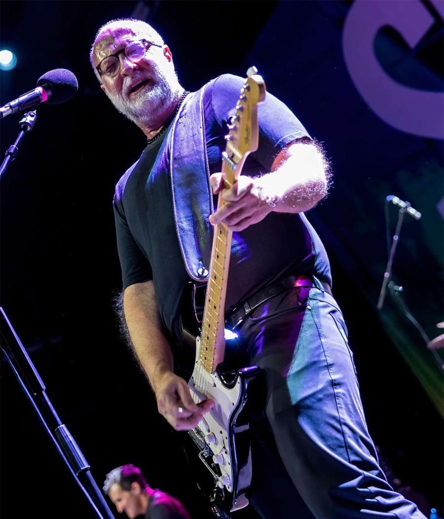 Musician performing on stage with an electric guitar.