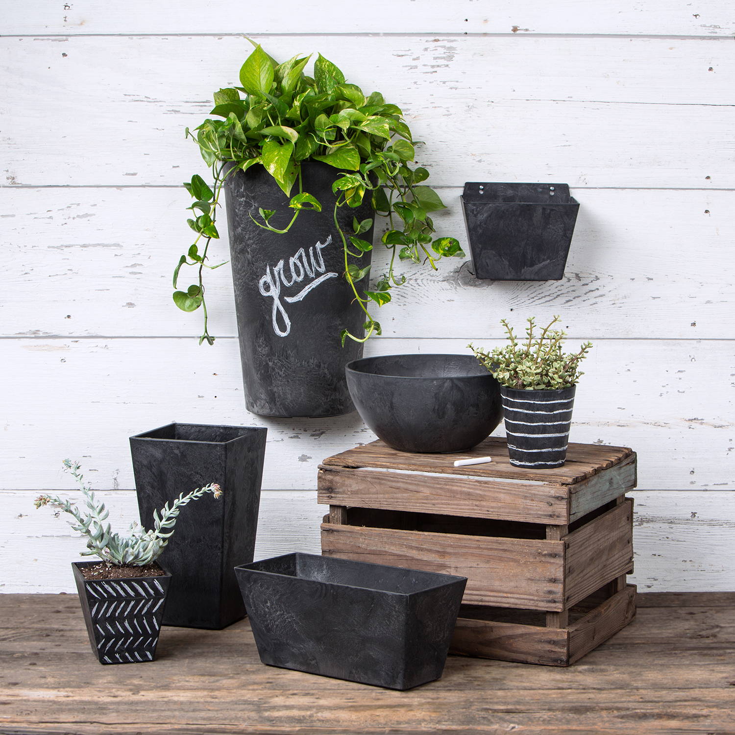 Several black planters of different shapes are sitting and hanging on a wall