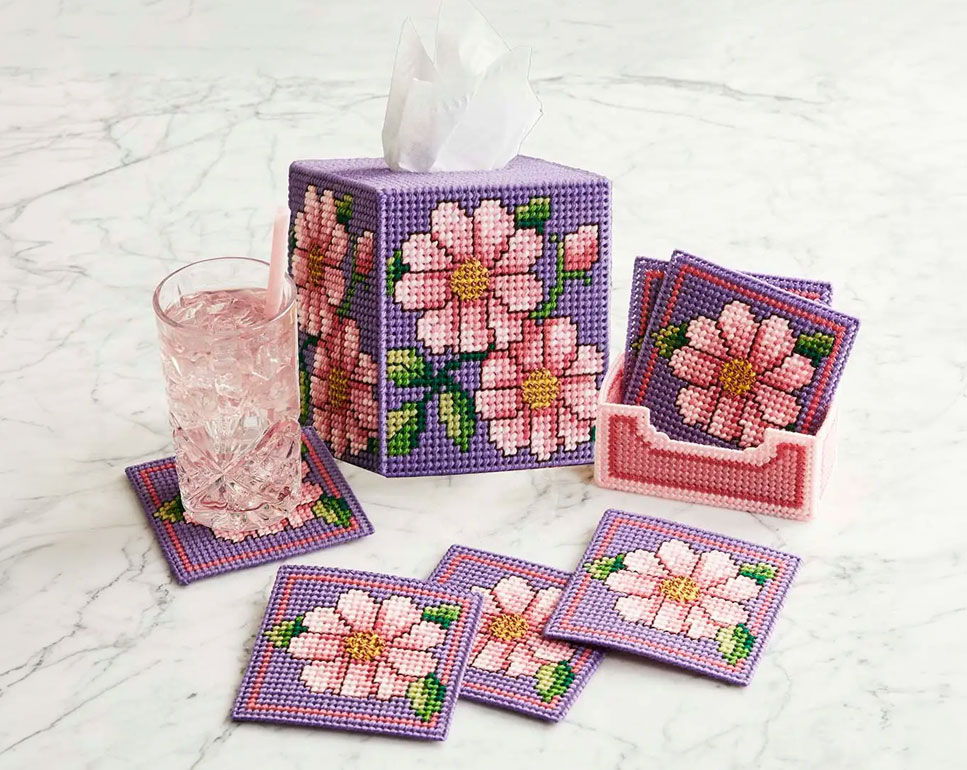 Tissue box and coasters with pink flower designs on a marble surface.