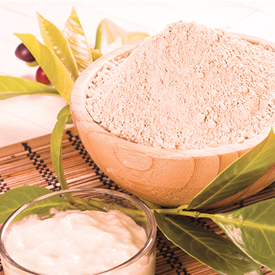 Bowls of flour with green leaves on a woven mat.