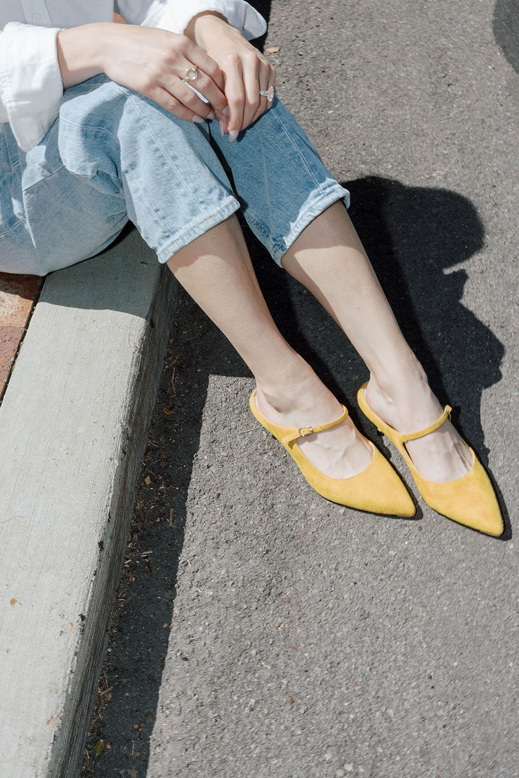 Person sitting on pavement wearing yellow shoes and light blue jeans.