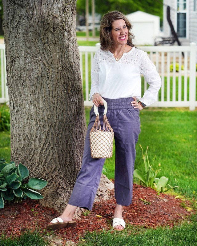 Woman standing in front of tree outside wearing white Seychelle long sleeve top.