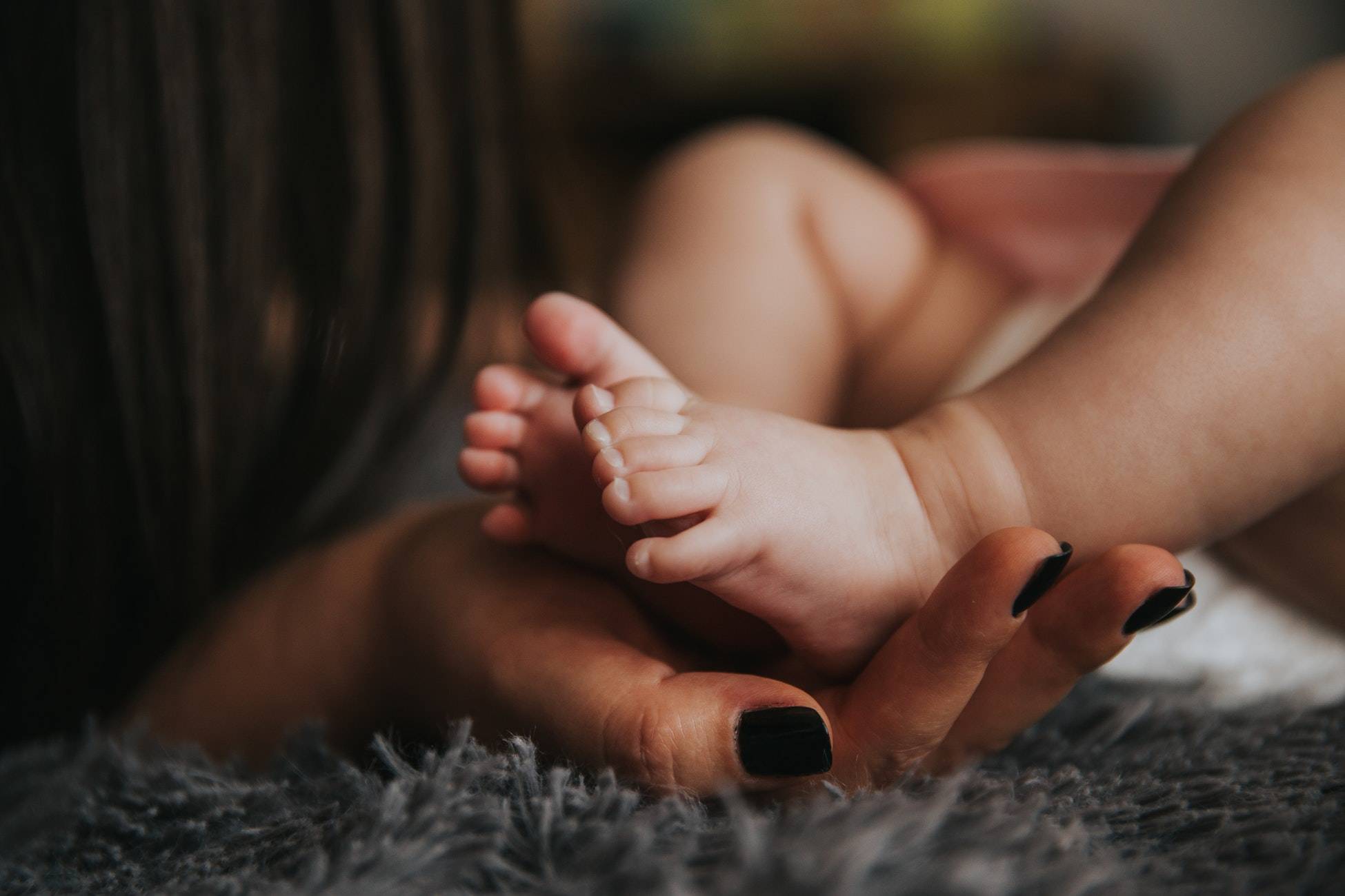 woman caressing foot of baby