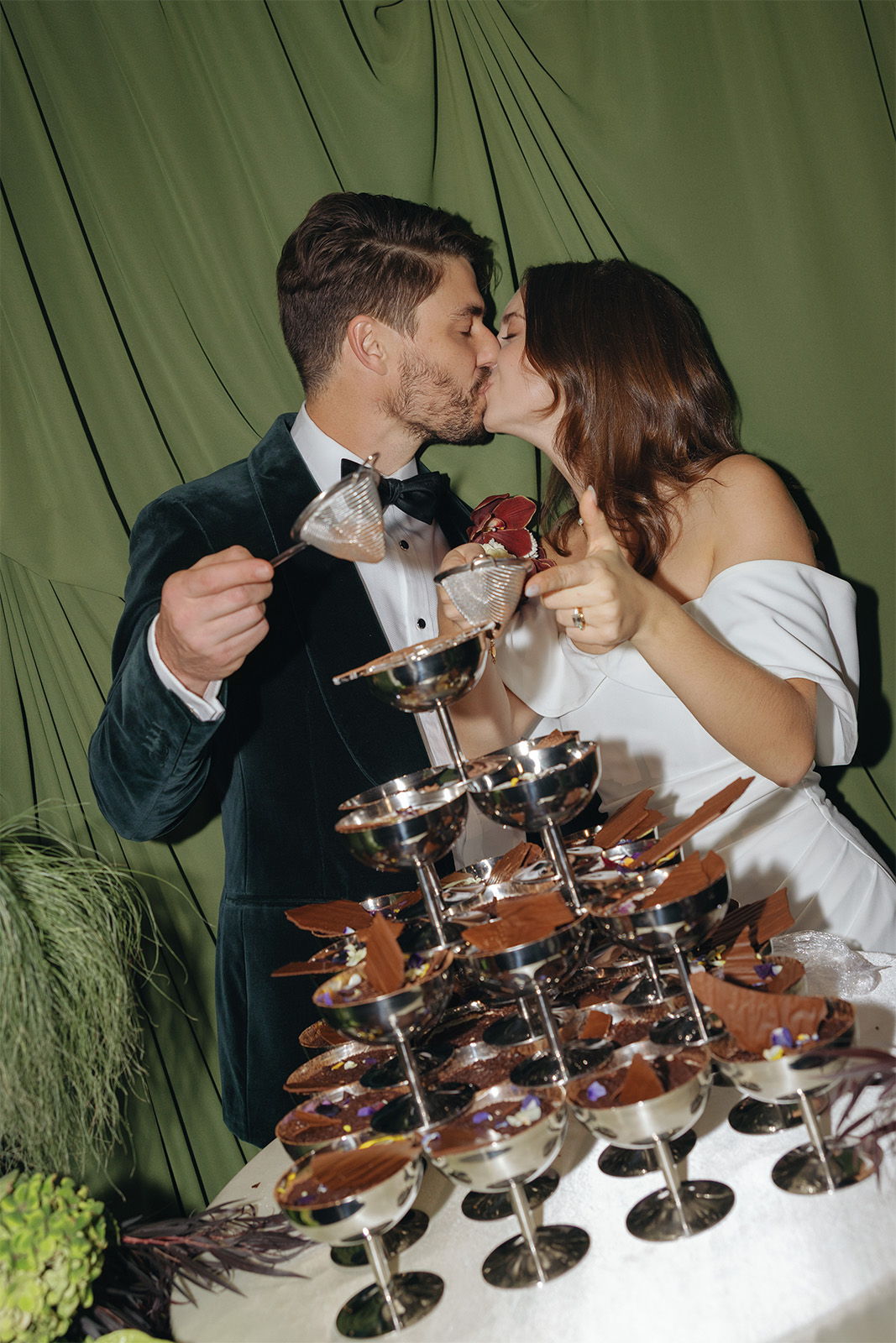 Couple kissing beside a champagne fountain at a celebration.
