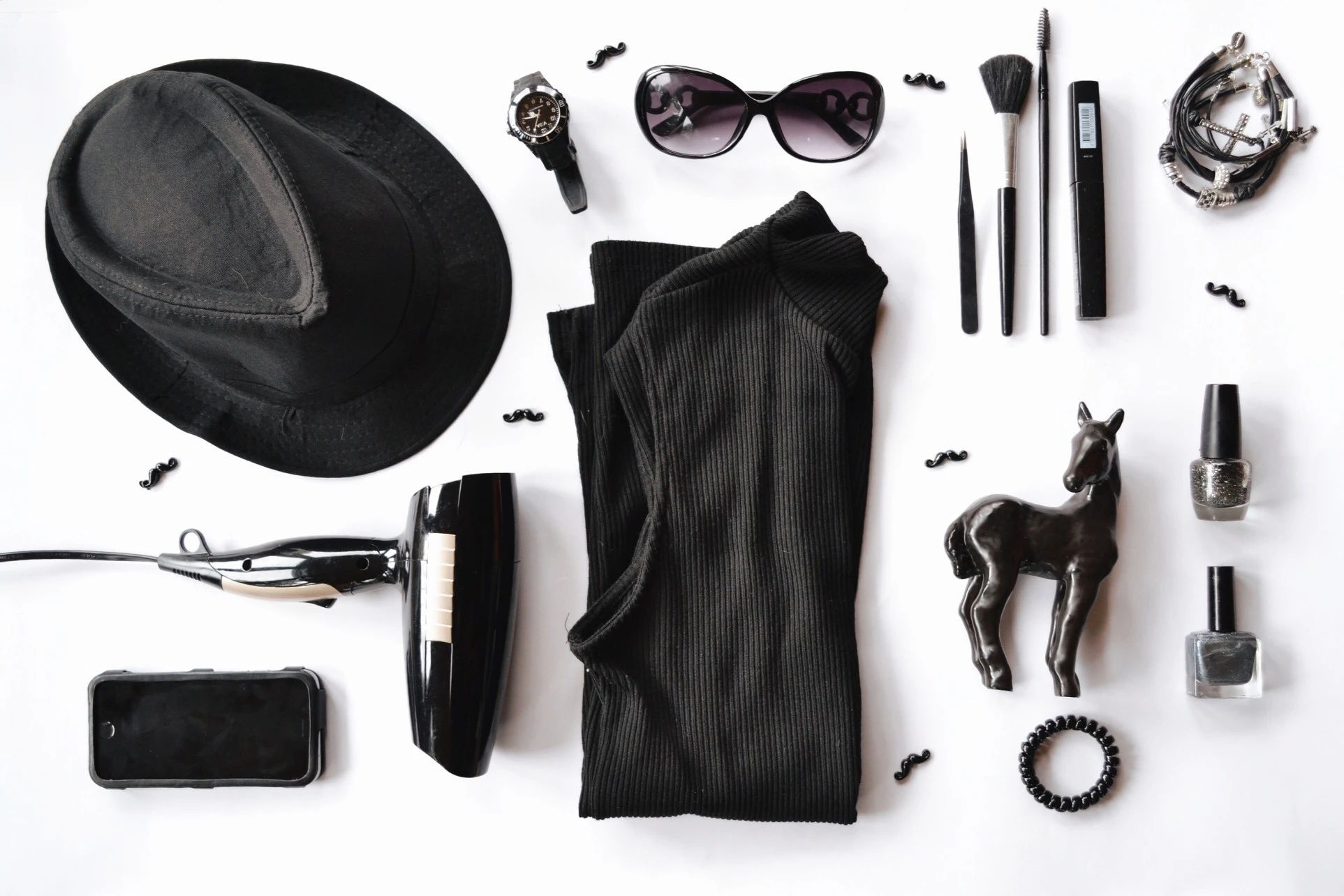 Flat lay of black clothing and accessories on a white background.