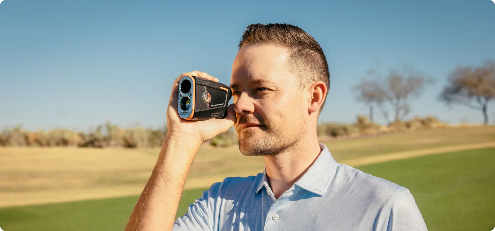 Man using a golf rangefinder on a sunny golf course.