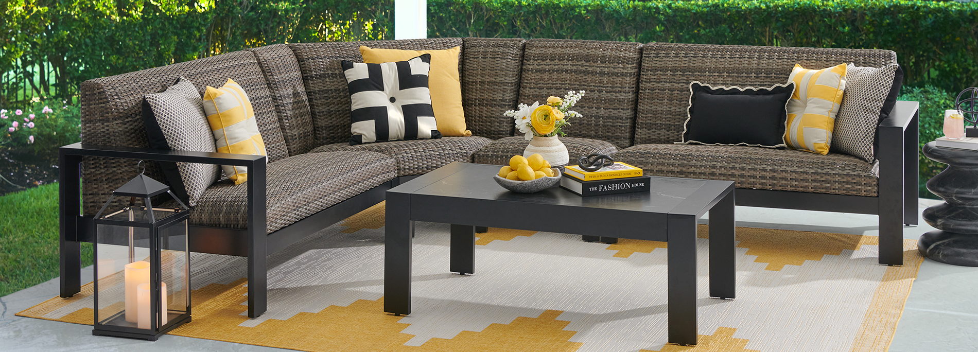 Outdoor sectional sofa with cushions and a coffee table on a patterned rug.