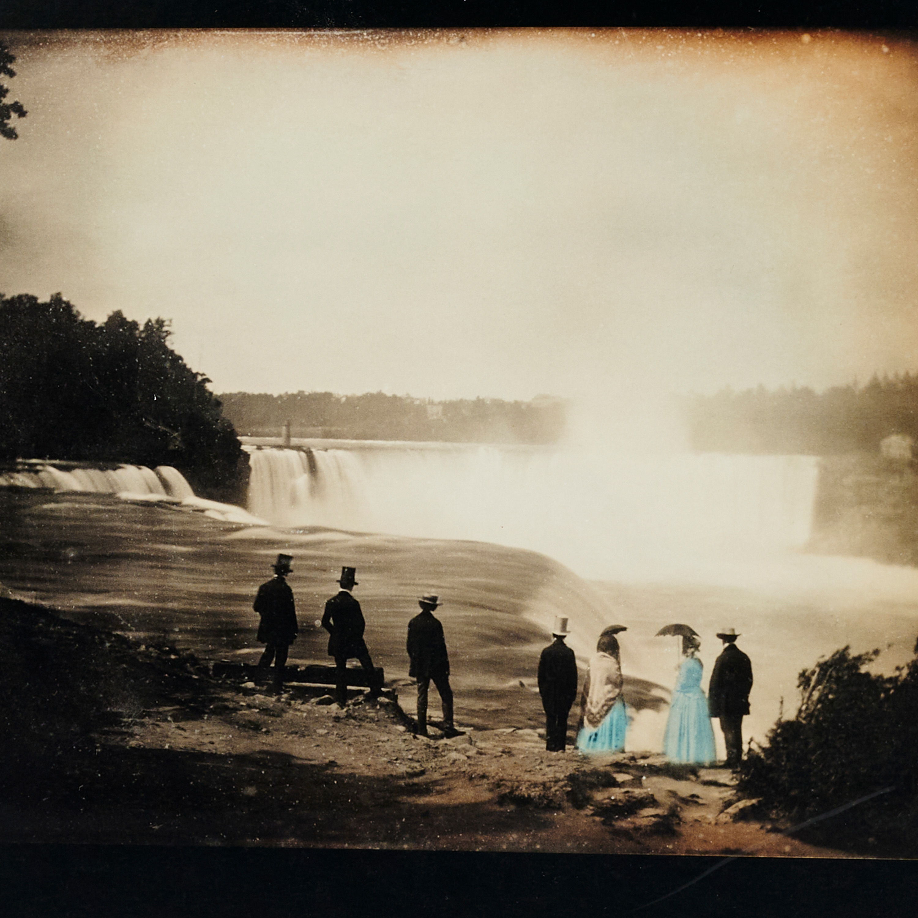 Six figures near a waterfall, one in a blue dress.