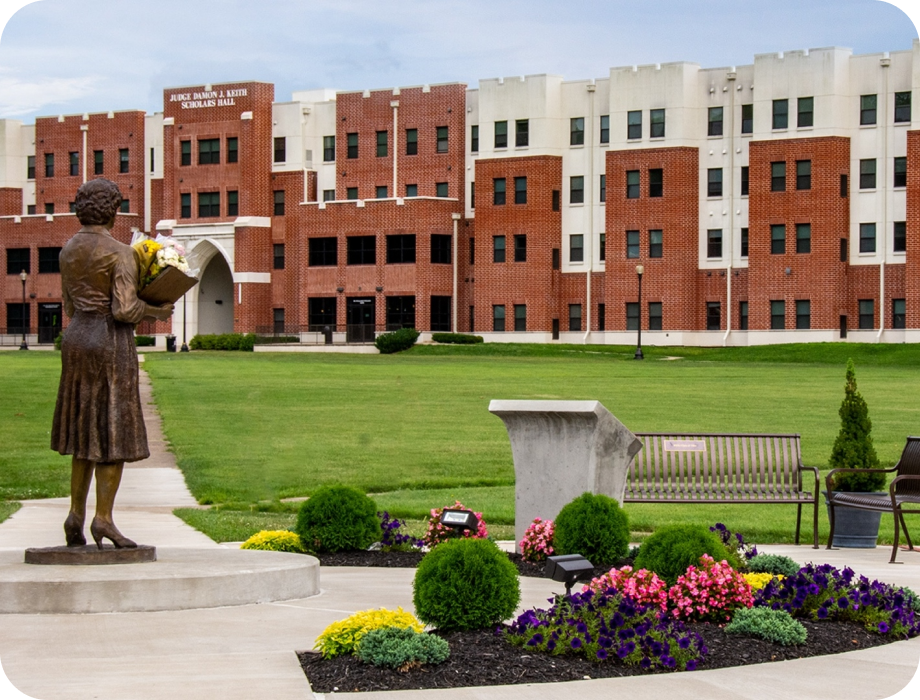 Statue in a landscaped area with a building in the background.