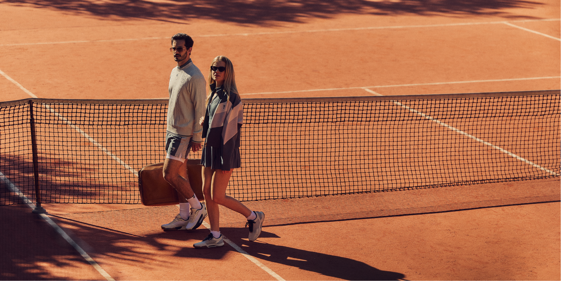 A man and woman walking on a tennis court.