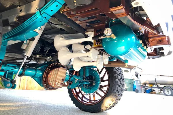 Close-up front wheel and teal suspension on Jacob's lifted Chevrolet Silverado photo 4