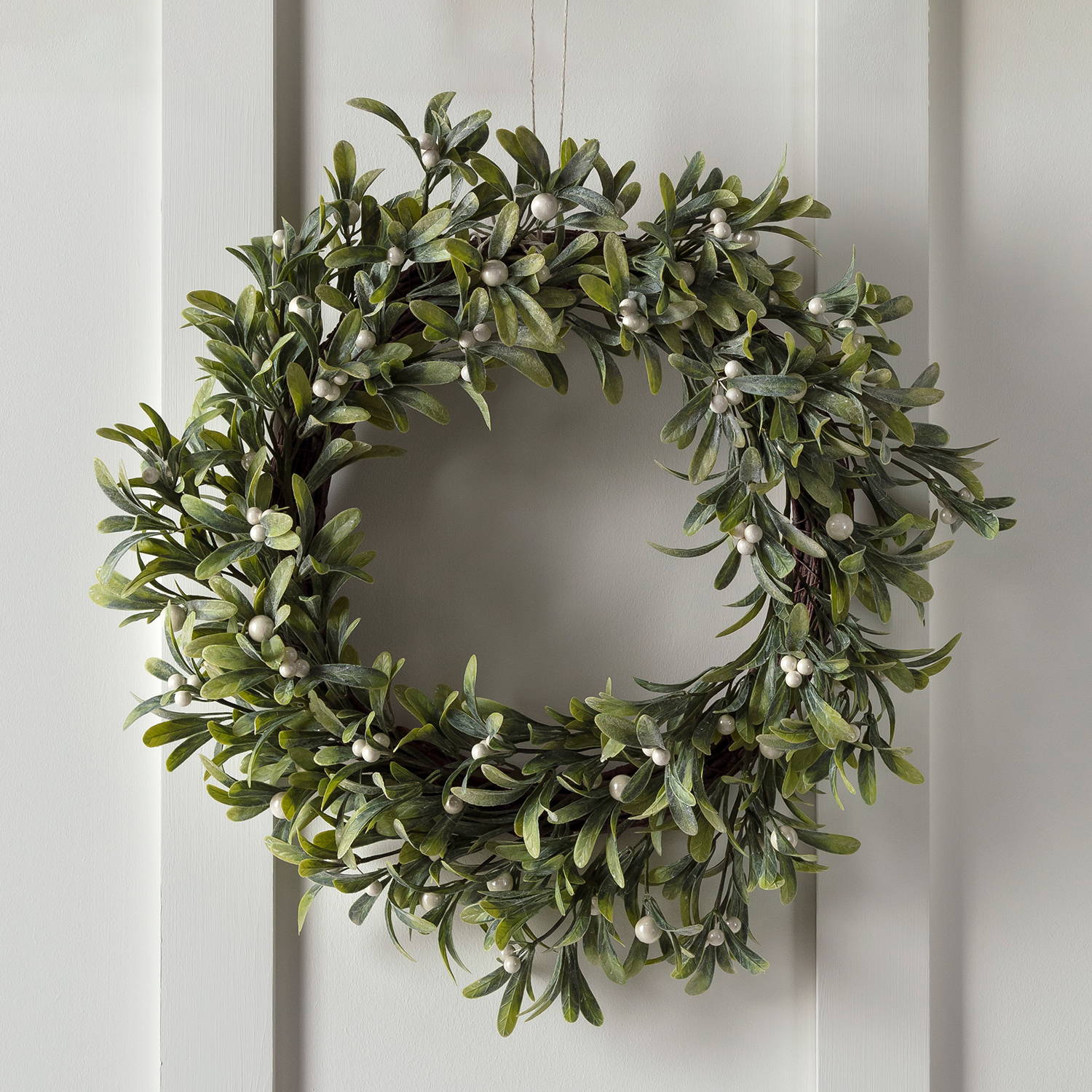 green leaf mistletoe Christmas wreath hung up on white background