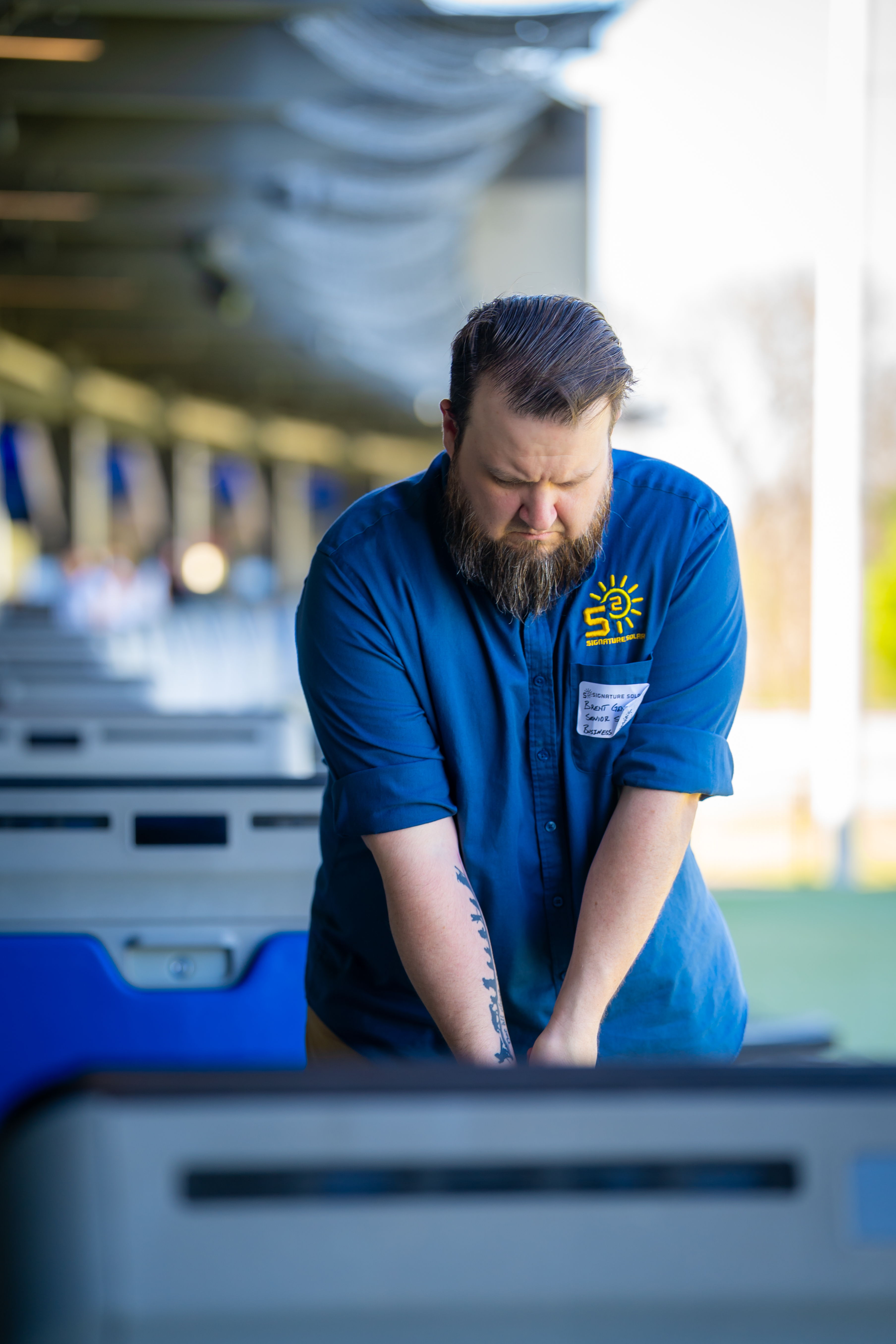 A man in a blue shirt practicing golf swings at a driving range.