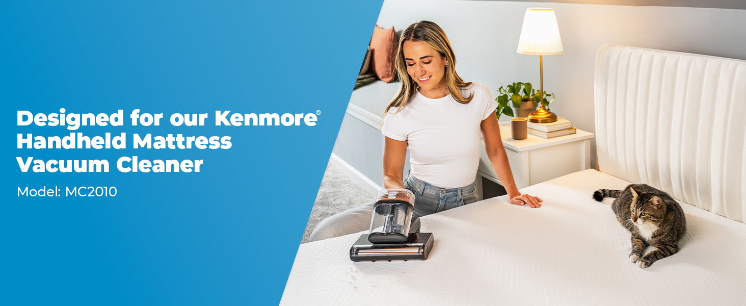 A woman cleans a mattress with a vacuum. A cat lays on the bed.