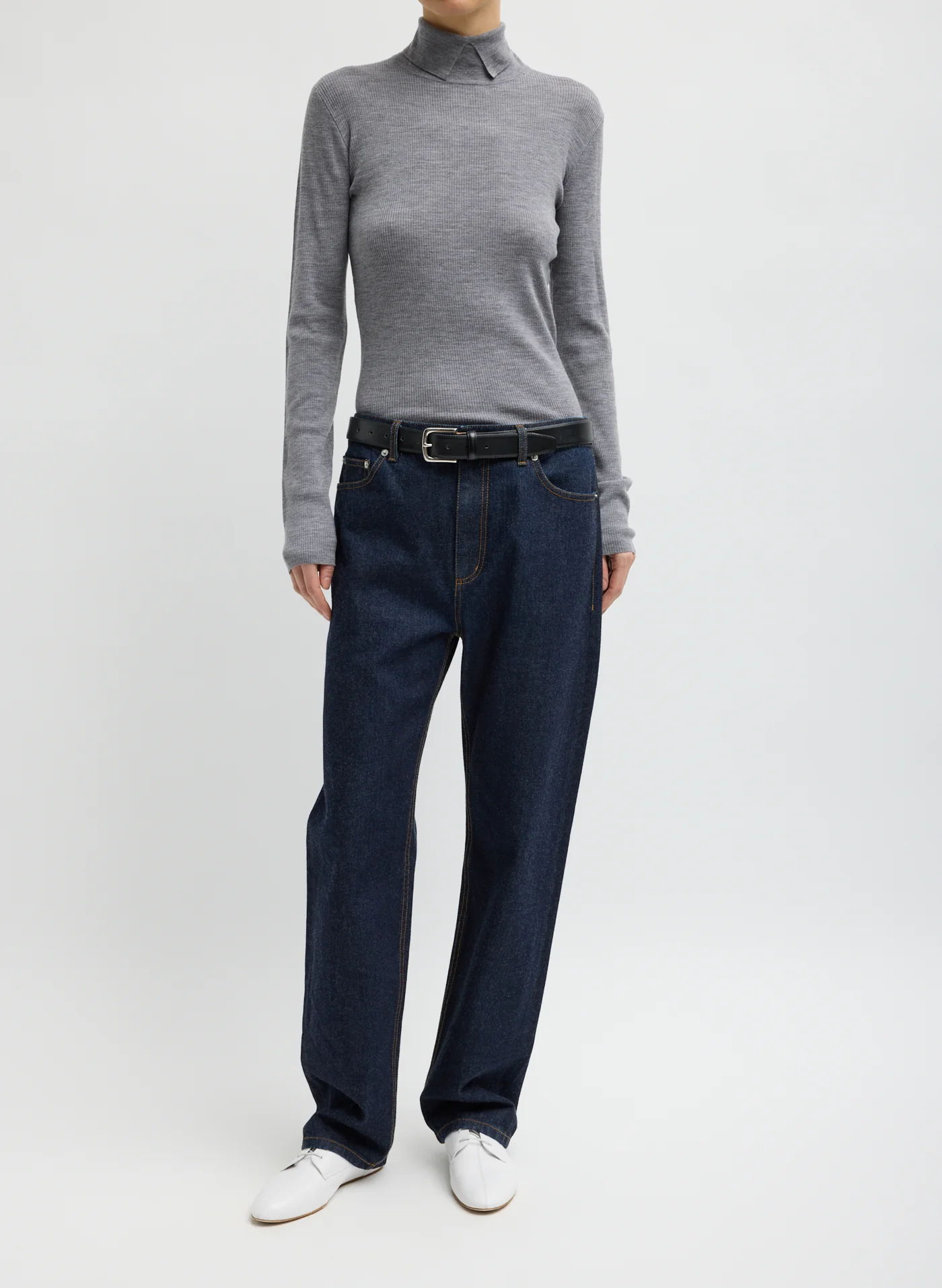 Person wearing a gray turtleneck, blue jeans, and white sneakers.