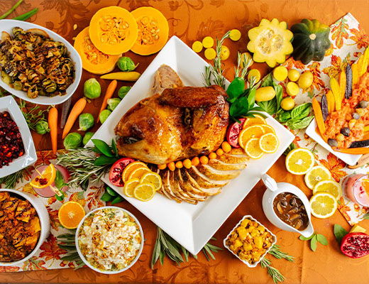 A festive table spread with roasted chicken, fruits, and various side dishes.