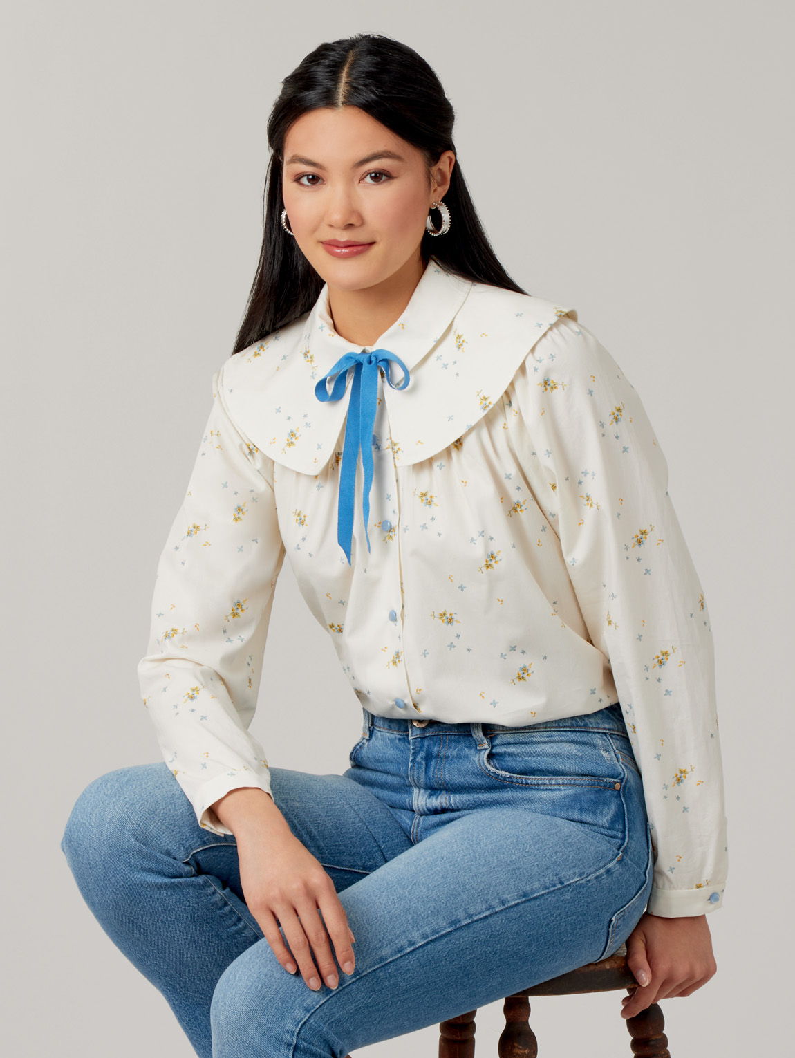 Young woman in a floral blouse with a large collar and blue ribbon.