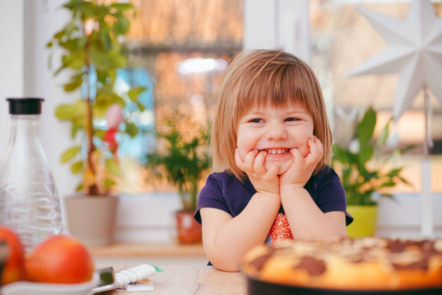 Child Sitting At The Table Smiling