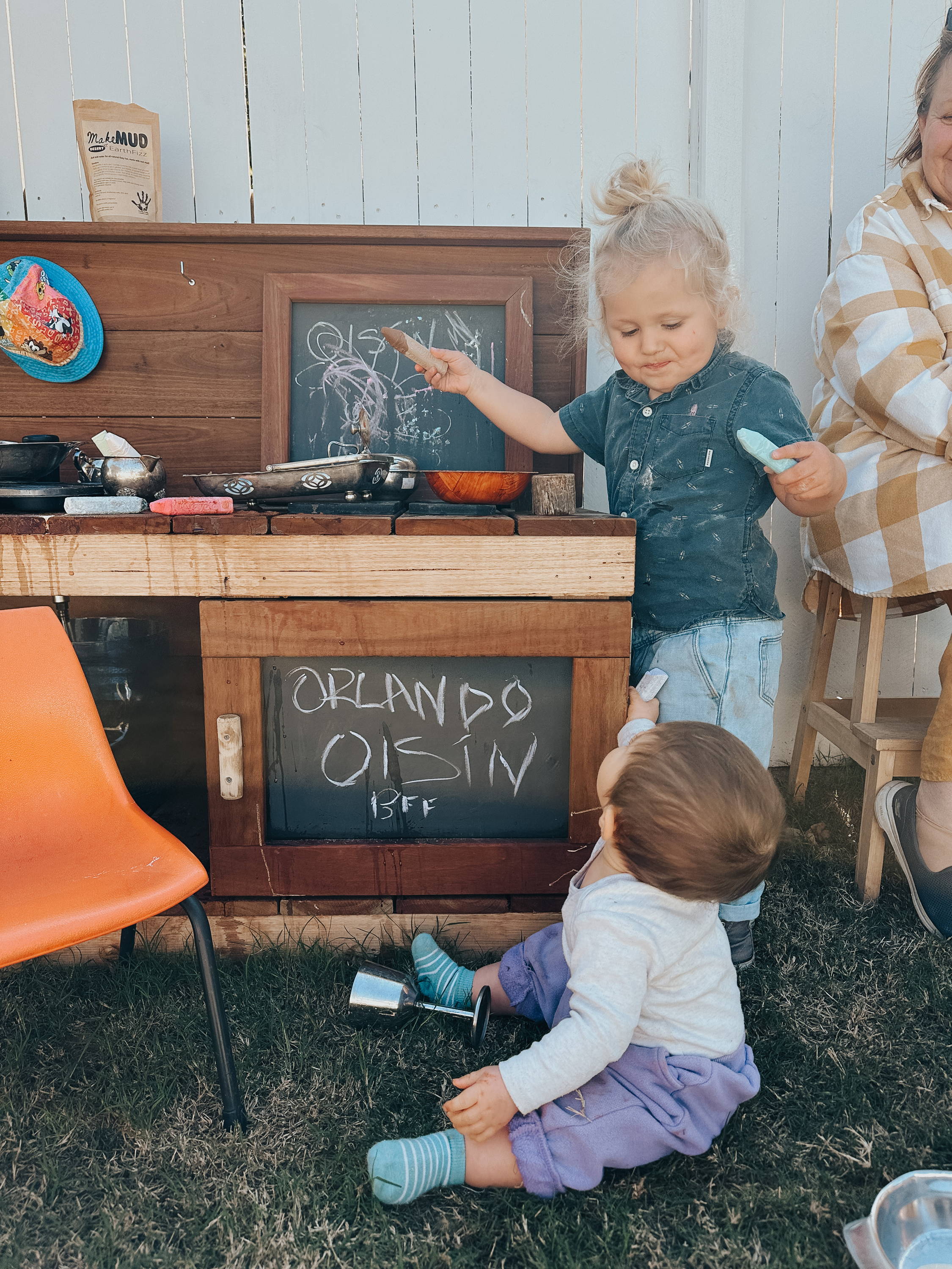 Children drawing with a chalk on a blackboard of a mudkitchen