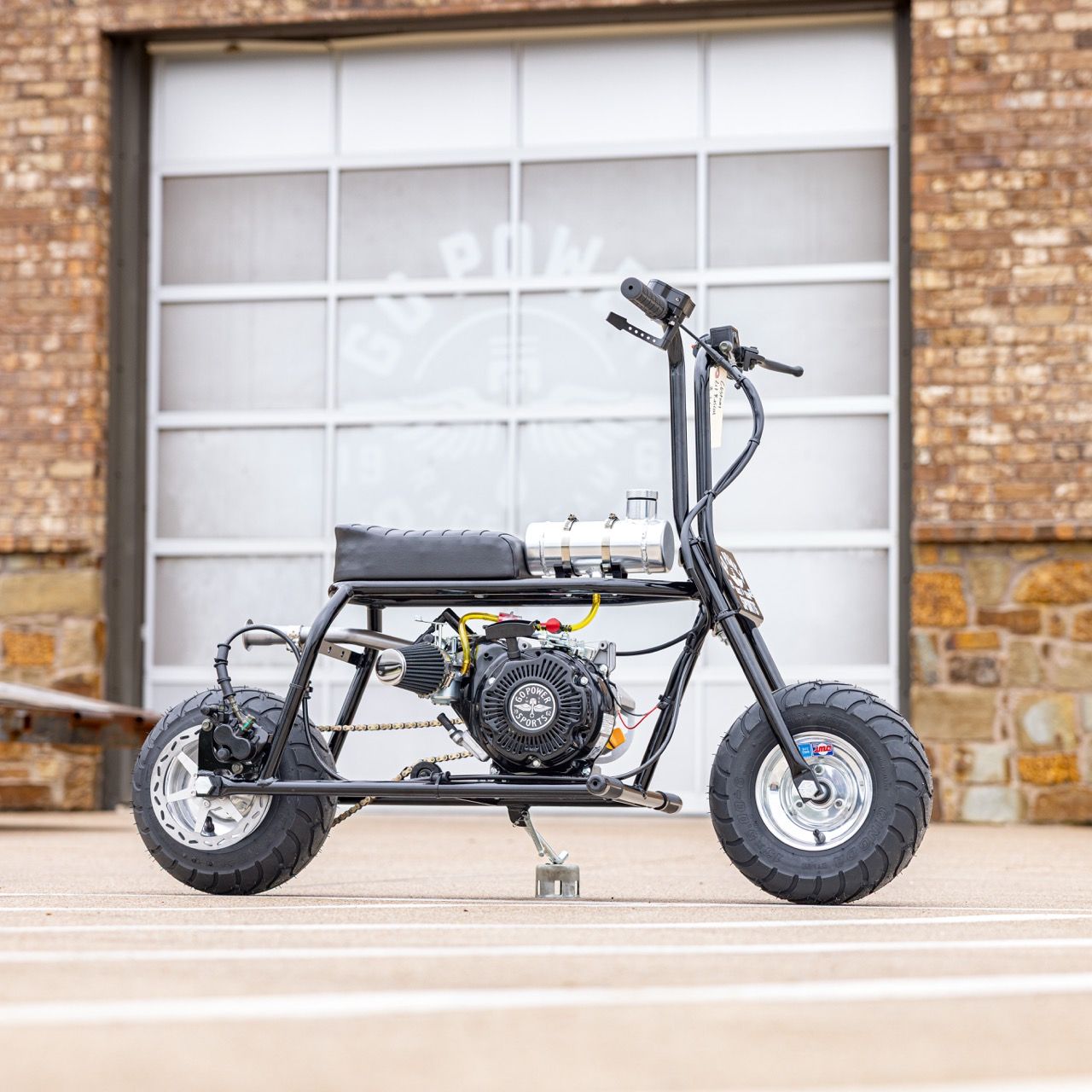A black mini bike with large tires parked in front of a garage door.
