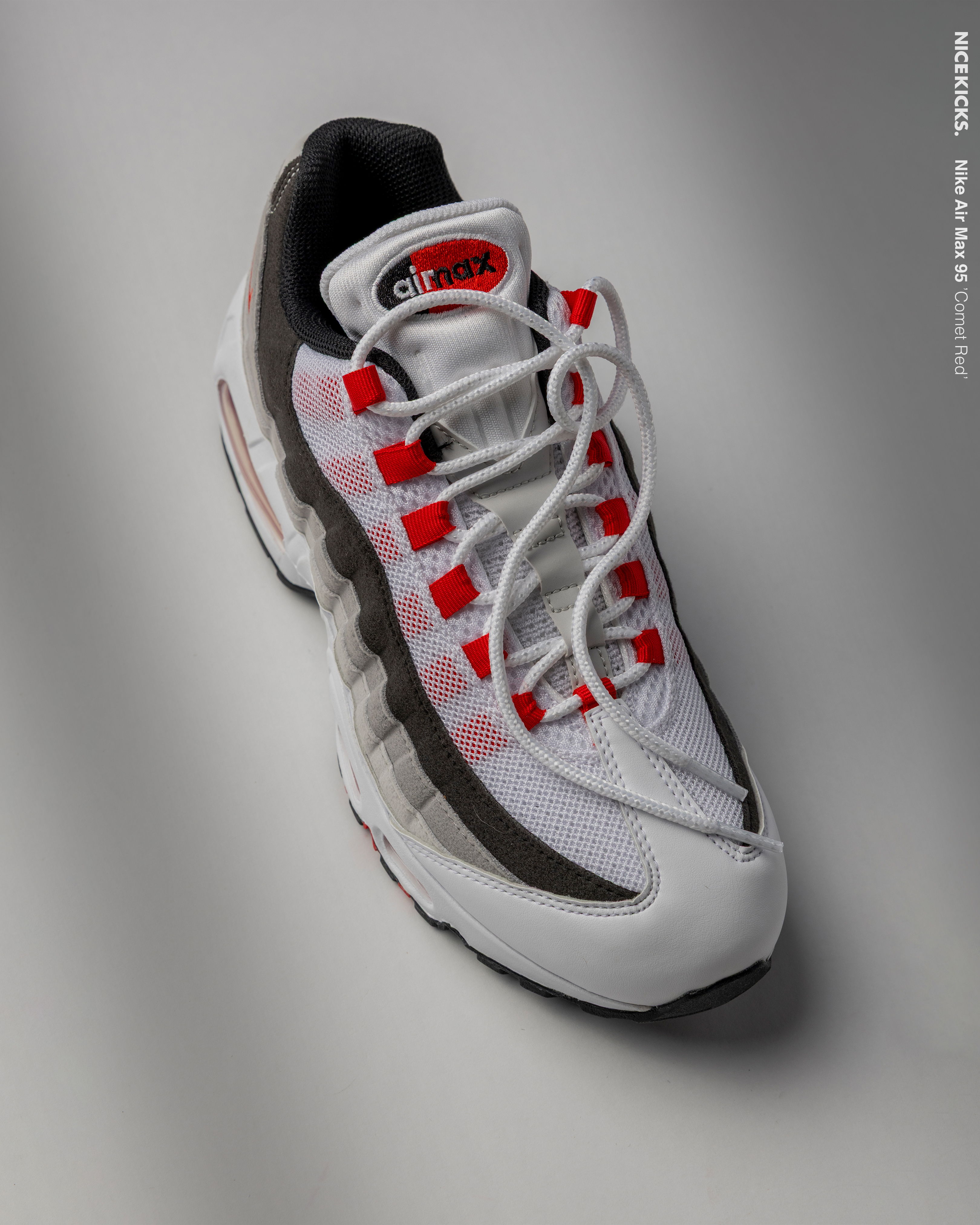 White and gray sneaker with red and black accents on a gray background.