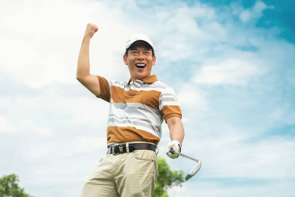 A golfer with a golf club celebrating on the course