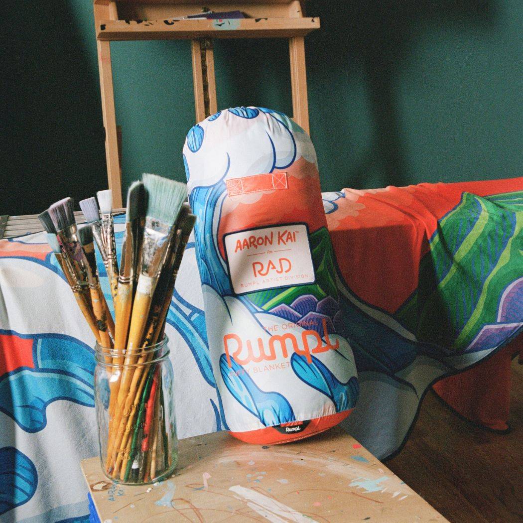A closer look at the Hokusai Great Wave Stuff Sack and Everywhere Towel, propped up near a jar of paintbrushes in Aaron Kai's studio.